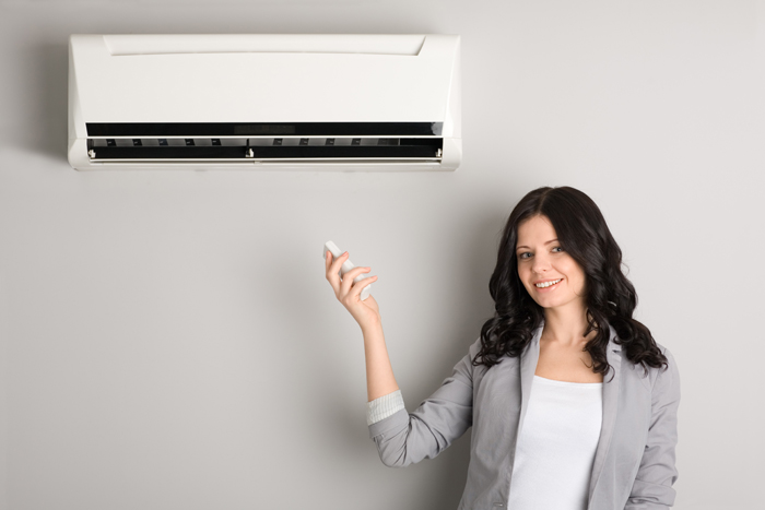 girl pointing a remote control at a heat pump